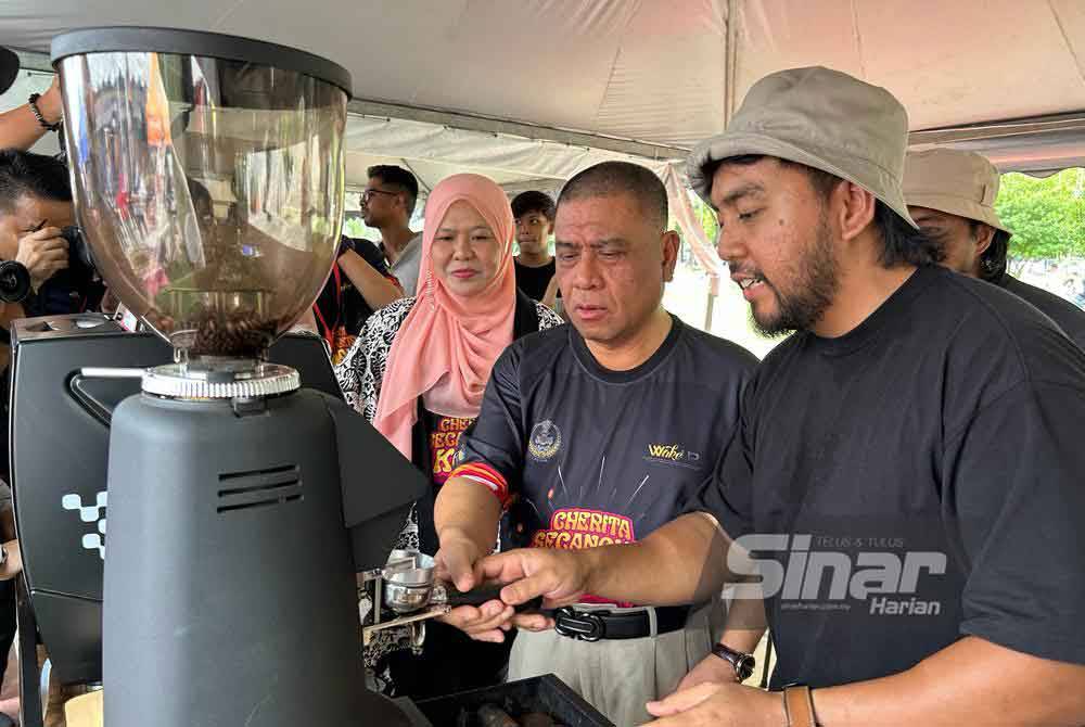 Saarani (dua dari kanan) mencuba sendiri kaedah penyediaan minuman kopi ketika melawat reruai pada Karnival Kopi Perak 'Cherita Secangkir Kopi' di Ipoh.
