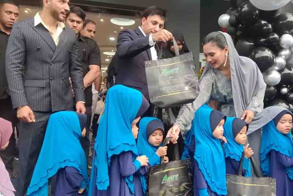Farooq (tengah) bersama Fasha Sandha memberi sumbangan kepada anak-anak yatim selepas pelancaran kedai pakaian Al Faro cawangan Johor di Uda Business Centre, Bandar Baru Uda, Johor Bahru pada Ahad.