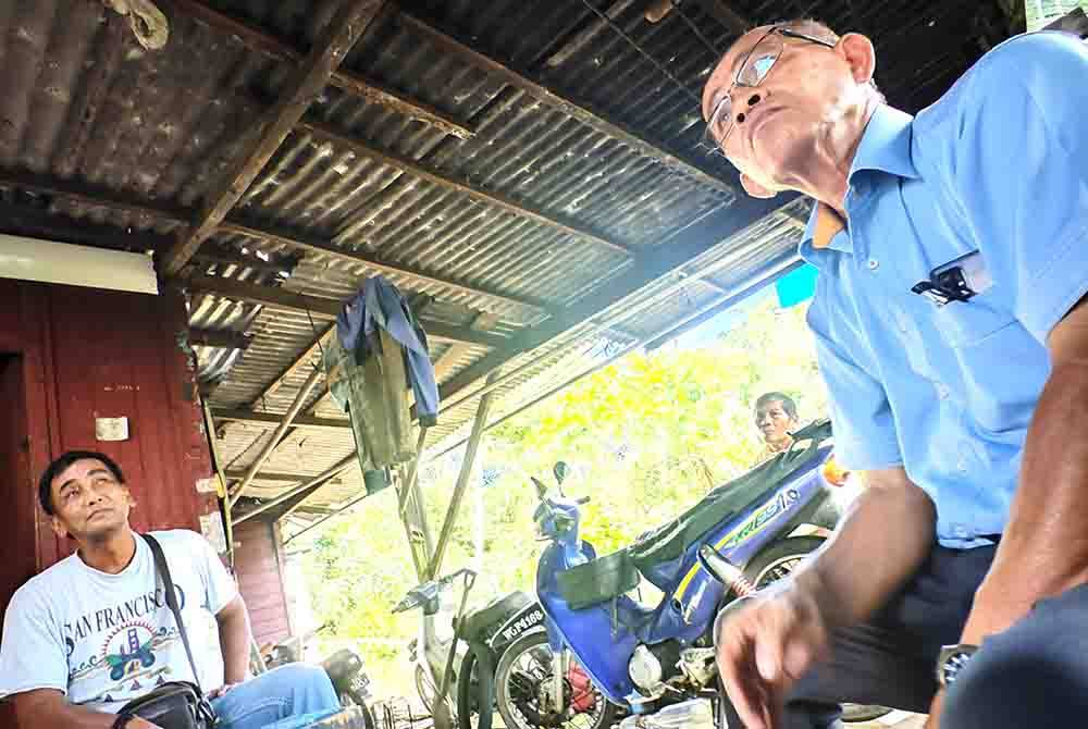 Abd Latif (kanan) melihat keadaan bumbung rumah Juhan (kiri).