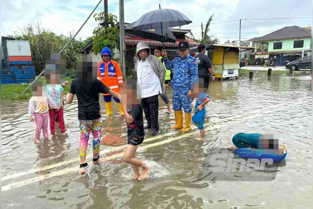 Nik Mohamed (tengah) yang turun padang meninjau keadaan banjir di Rantau Panjang.