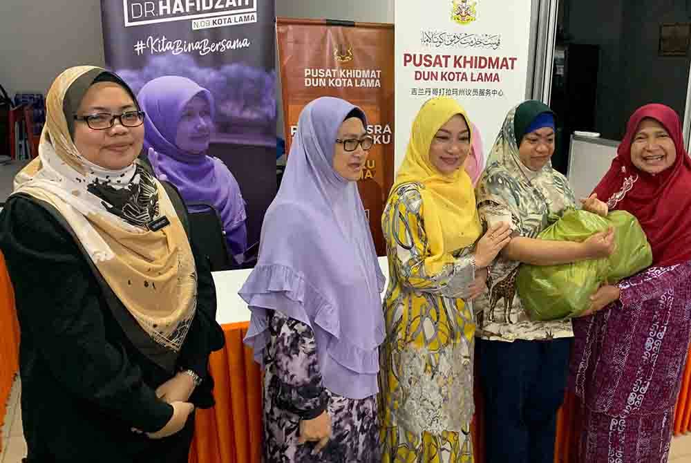 Dr Hafidzah (kanan) menyampaikan sumbangan kepada penjaga OKU sempena Sambutan Hari OKU DUN Kota Lama pada Ahad.