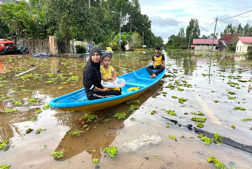 Penduduk menggunakan perahu untuk keluar dari rumah mereka ke kawasan PPS Masjid Mukim Padang Licin.