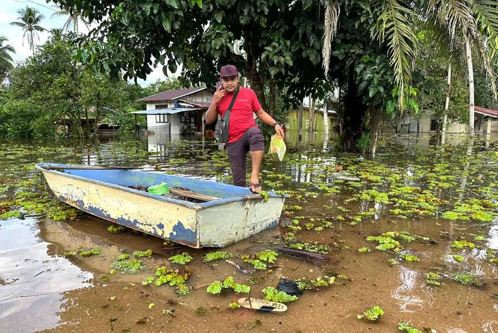 Zamri melangkah ke dalam perahu dalam banjir yang dipenuhi kiambang.