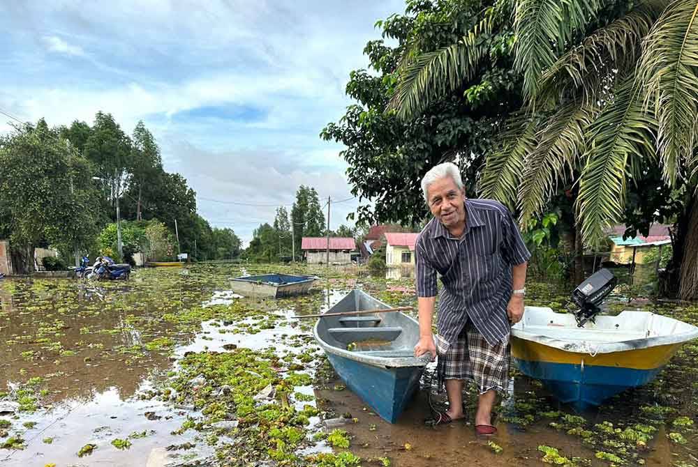 Penduduk menarik perahu dari dalam banjir yang dipenuhi kiambang.