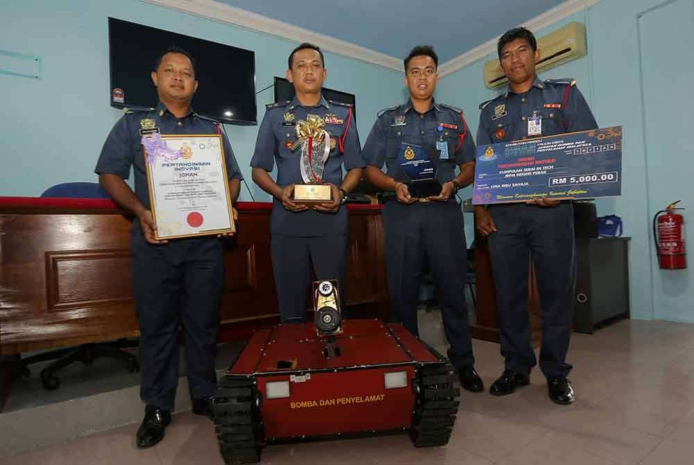 Ahmad Noor Syamsi (tiga, kanan) bersama pegawainya menunjukkan sijil dan trofi serta replika cek yang dimenangi pada Pertandingan Inovasi Jabatan Bomba dan Penyelamat 2023 ketika ditemui di Balai Bomba dan Penyelamat Bagan Serai semalam. - Foto Bernama