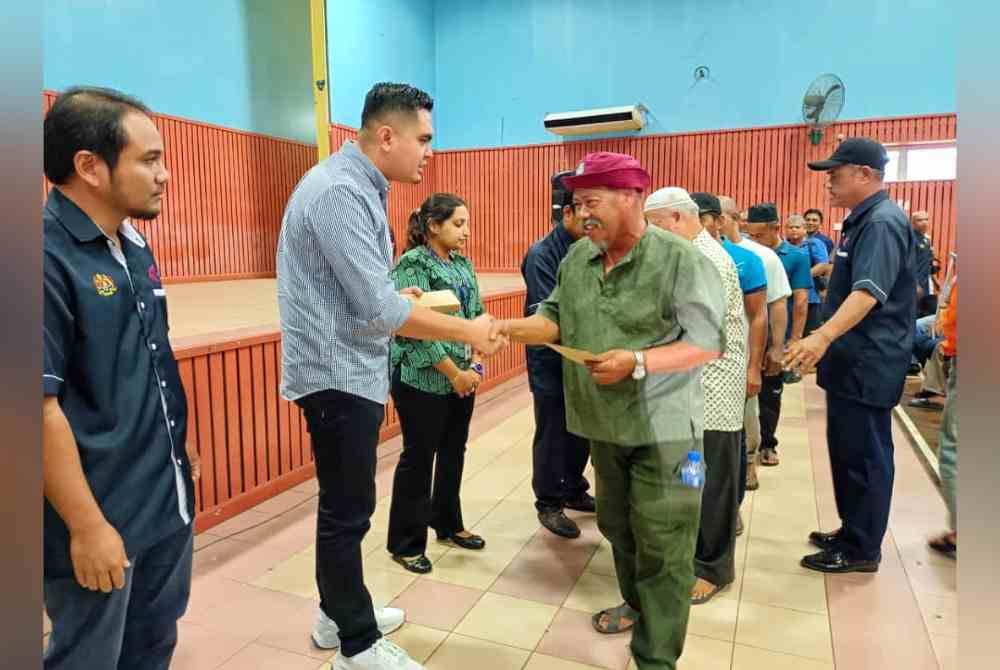 Dr Muhamad Akmal (dua dari kiri) ketika menyampaikan bantuan sara hidup kepada nelayan daerah Jasin di Dewan Ahmad Ithnin, Merlimau Pasir pada Isnin