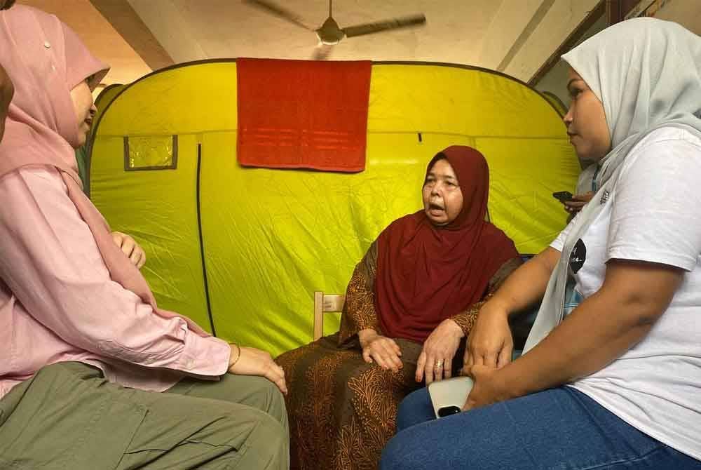 Fadhlina (kiri) melawat penghuni di PPS SK Gual Tinggi, Rantau Panjang pada Isnin.