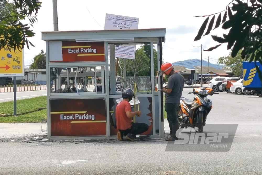 Dua pekerja melihat kerosakan di pondok bayaran parkir kenderaan di Dataran Rimba Square di Kuala Nerus.