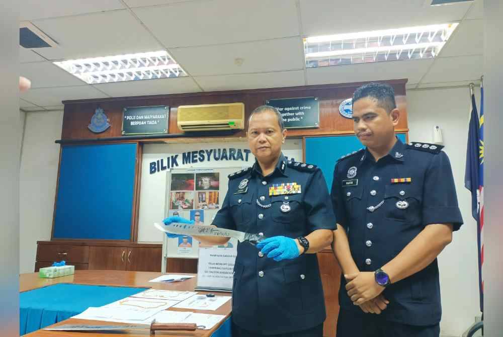 Ahmad Adnan (kiri) menunjukkan senjata digunakan kumpulan penjenayah dalam kes samun bersenjata melibatkan seorang warga emas, 22 November lalu.