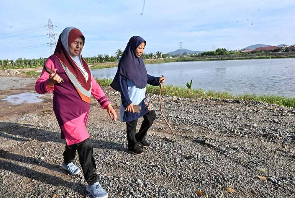 Norzila (dua dari kiri) terpaksa membawa ranting kayu kerana bimbang dengan kehadiran anjing liar di
Kolam Takungan Banjir Semabok, Taman Semabok Perdana.