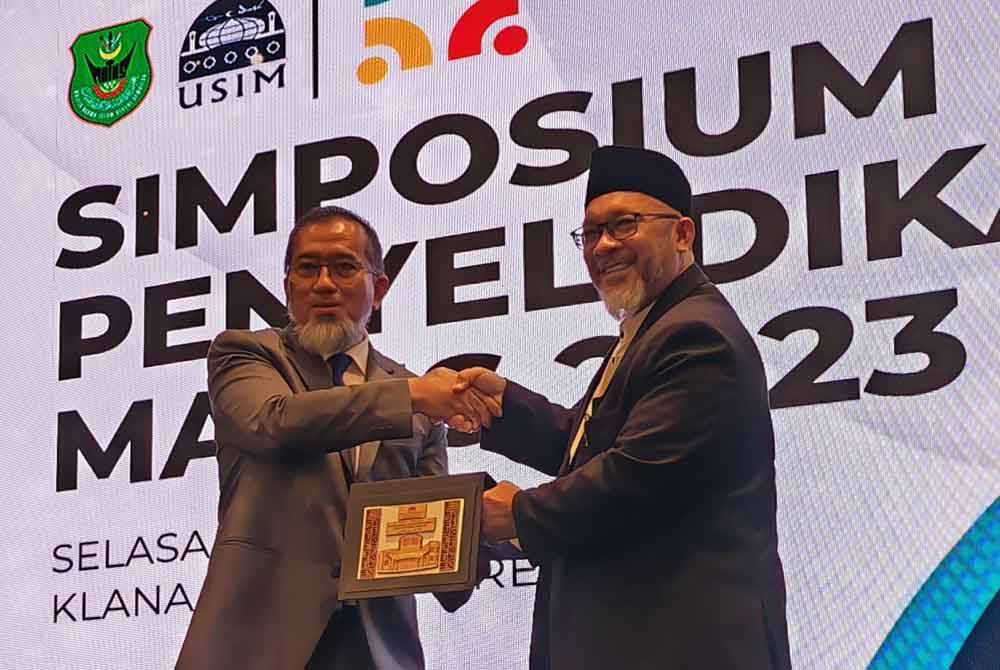 Faudzinaim (kiri) menyerahkan cenderahati kepada Muhammad Tauffik.