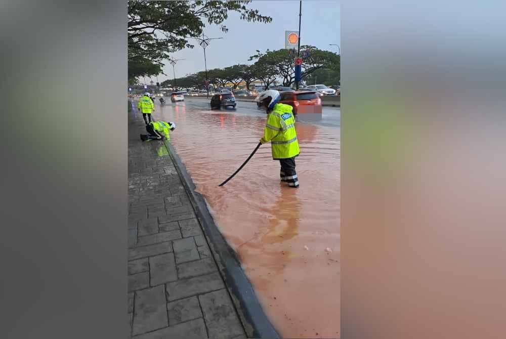 Anggota polis trafik membersihkan longkang yang tersumbat bagi melancarkan pergerakan lalu lintas di Skudai.
