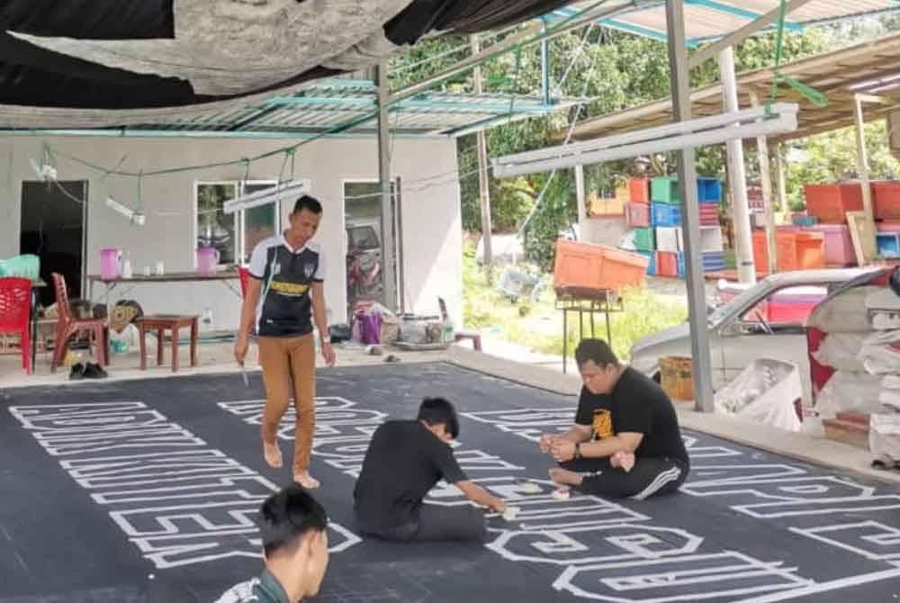 Geng 12 FC Terengganu menyiapkan sepanduk sempena perlawanan akhir Piala Malaysia.