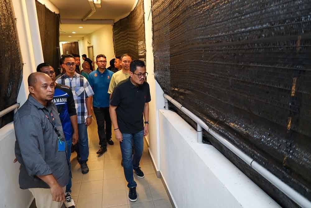 Harrison (depan, kanan) bersama-sama wakil agensi kerajaan dan penduduk meninjau pemasangan jaring di koridor apartmen pada Rabu.