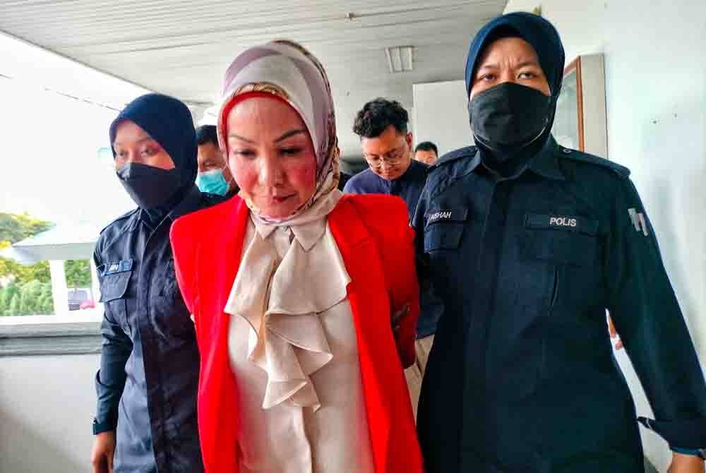 Mariyah (tengah) ketika dibawa keluar dari Mahkamah Seksyen Melaka pada Khamis.