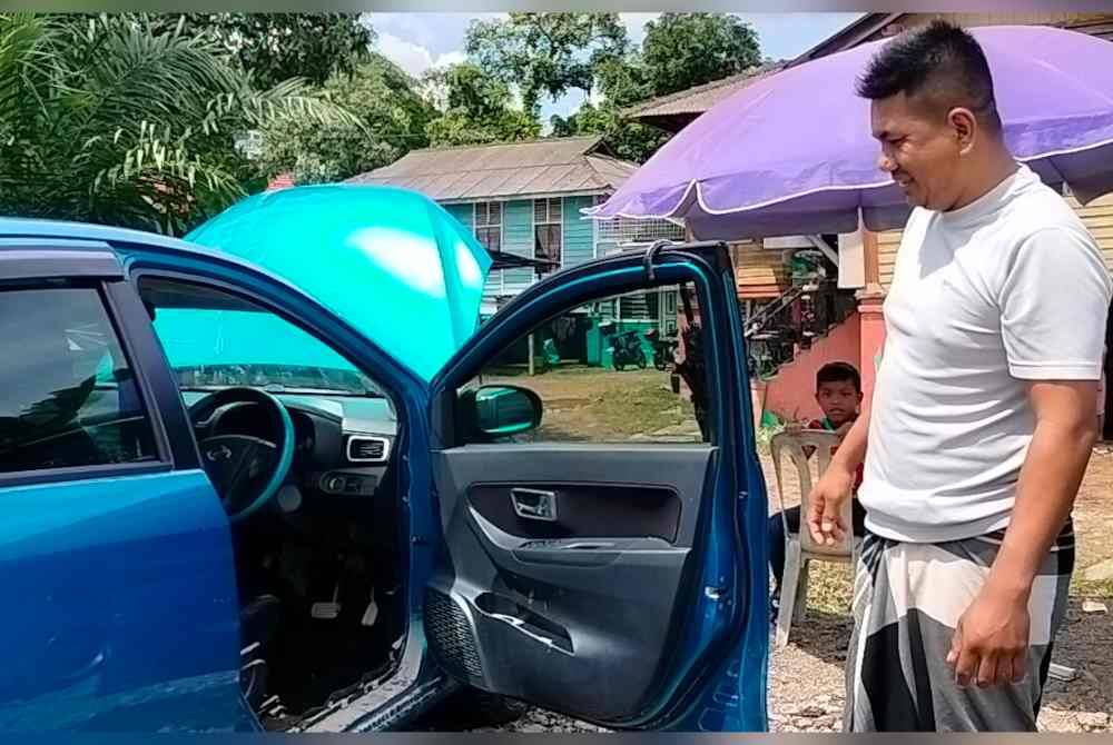 Penduduk menunjukkan kereta yang rosak akibat dinaiki air banjir di Kampung Mohd Amin Johor Bahru.