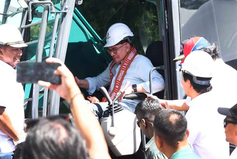 Anwar mengendalikan jengkaut sebagai simbolik pecah tanah projek Empangan Hidroelektrik Ulu Padas di Ulu Tomani, Kemabong hari ini. - Foto Bernama