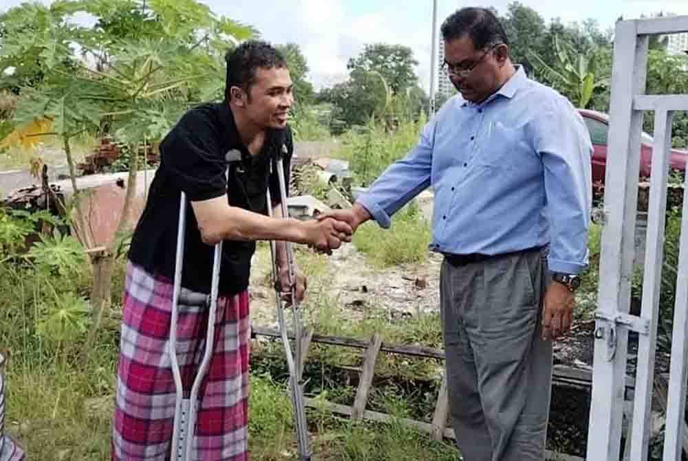 Mohd Ridzuan (kiri) bersalaman dengan Mas Imran di hadapan rumahnya di rumahnya di Kampung Plentong Baru, Masai pada Khamis.