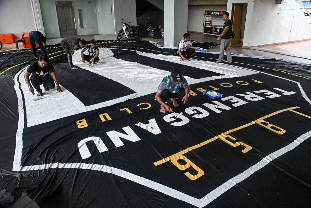 Penyokong Bola Sepak Terengganu FC atau lebih dikenali ‘Geng 12 FC’ menyiapkan bendera negeri dan kain rentang bersaiz gergasi menjelang kehangatan perlawanan akhir Piala Malaysia ketika tinjauan di Gong Badak. - Foto Bernama