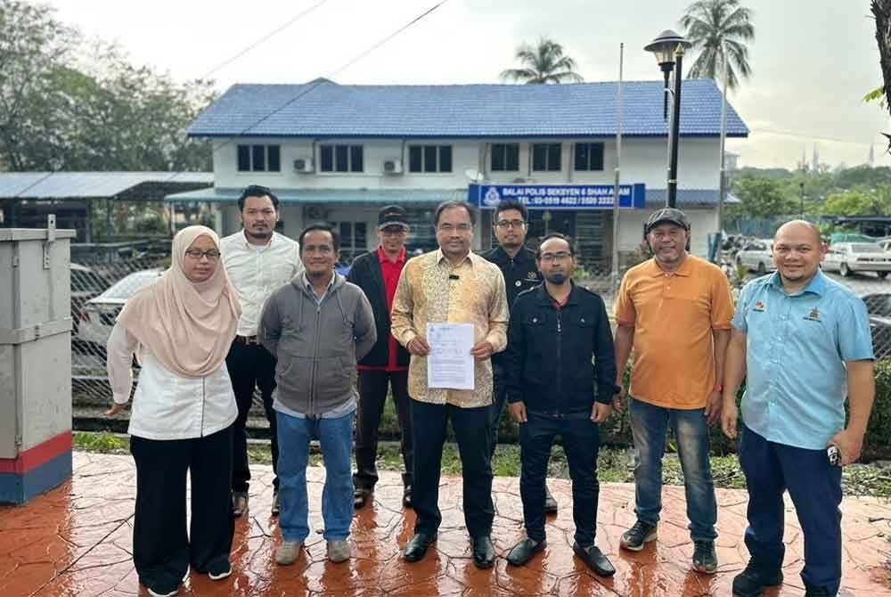  Azli (tengah) membuat laporan polis di Balai Polis Seksyen 6, Shah Alam pada Khamis.