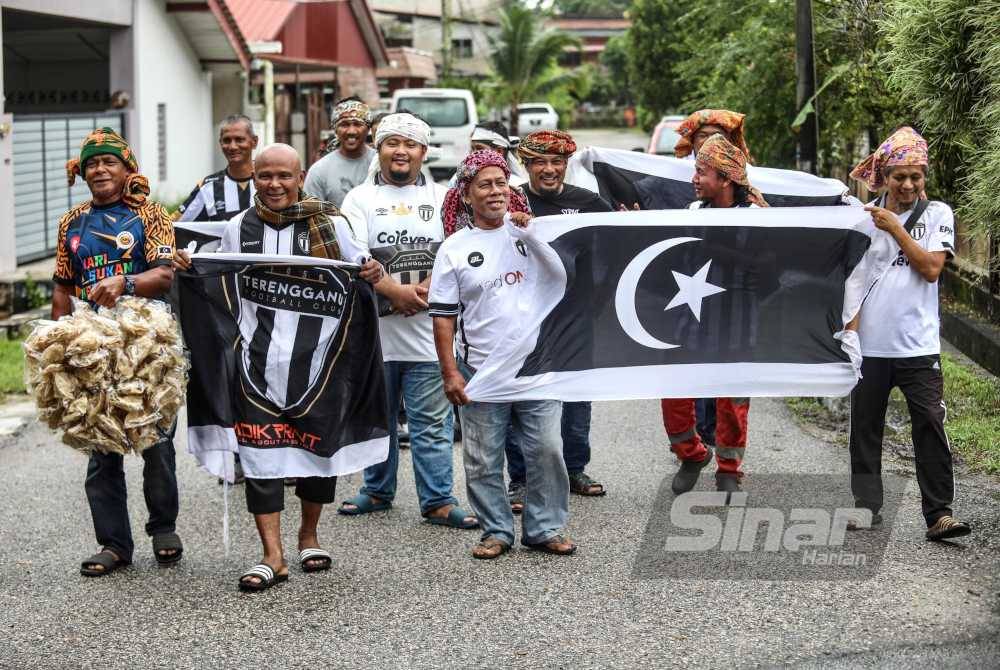 Muda (dua dari kiri) memakai kain batik bersama penyokong TFC lain sebelum bertolak ke SBNJ