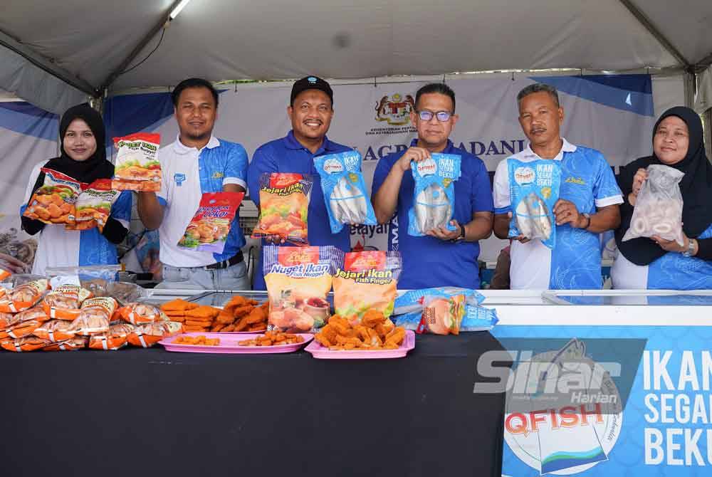 Azrin Shah dan kakitangan LKIM bersama pelbagai produk sejuk beku dan produk keluaran nelayan yang dijual di reruai LKIM pada Jumaat. - Foto Sinar Harian/Rosli Talib