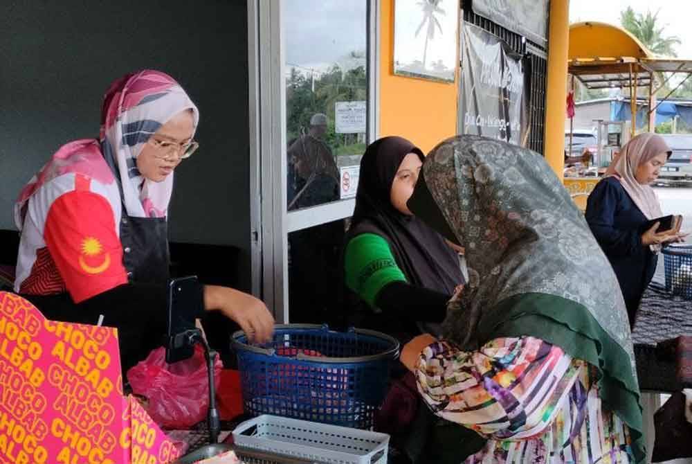 Nurulazma Syafiqah (kiri) ketika melayani pelanggannya.