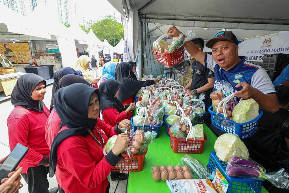 Pengunjung tidak melepaskan peluang membeli barangan keperluan harian dengan harga berpatutan di ruang kawasan jualan Agro Madani pada Program Setahun Bersama Kerajaan Madanidi pekarangan Stadium Nasional Bukit Jalil pada Jumaat. FOTO: Bernama