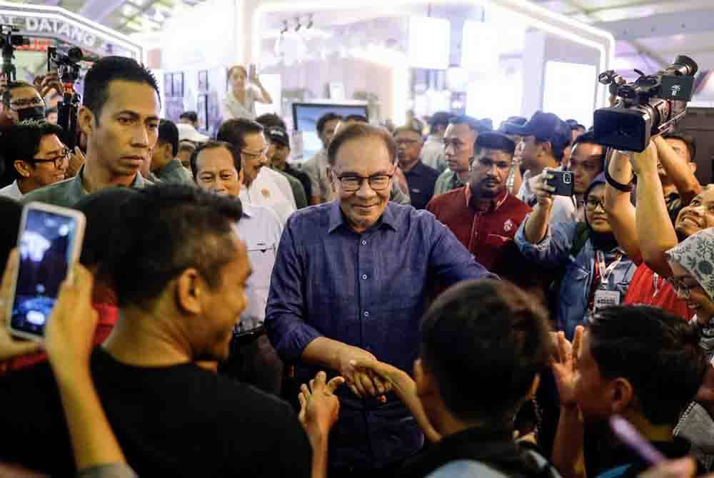 Anwar menyantuni orang ramai ketika menghadiri Program Setahun Bersama Kerajaan Madani di pekarangan Stadium Nasional Bukit Jalil hari ini. - Foto Bernama