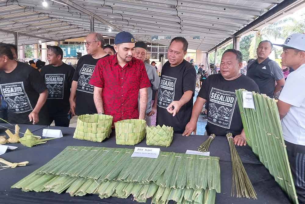 (Tengah) Khairul Firdaus melihat hasil kraftangan daripada tumbuhan nipah sempena program Seni di Lokasi:'Segaliud Artgriculture' pada Sabtu