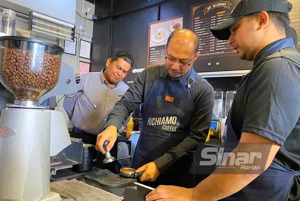 Fazli Rizal (tengah) cuba membuat kopi sambil dibantu oleh barista.