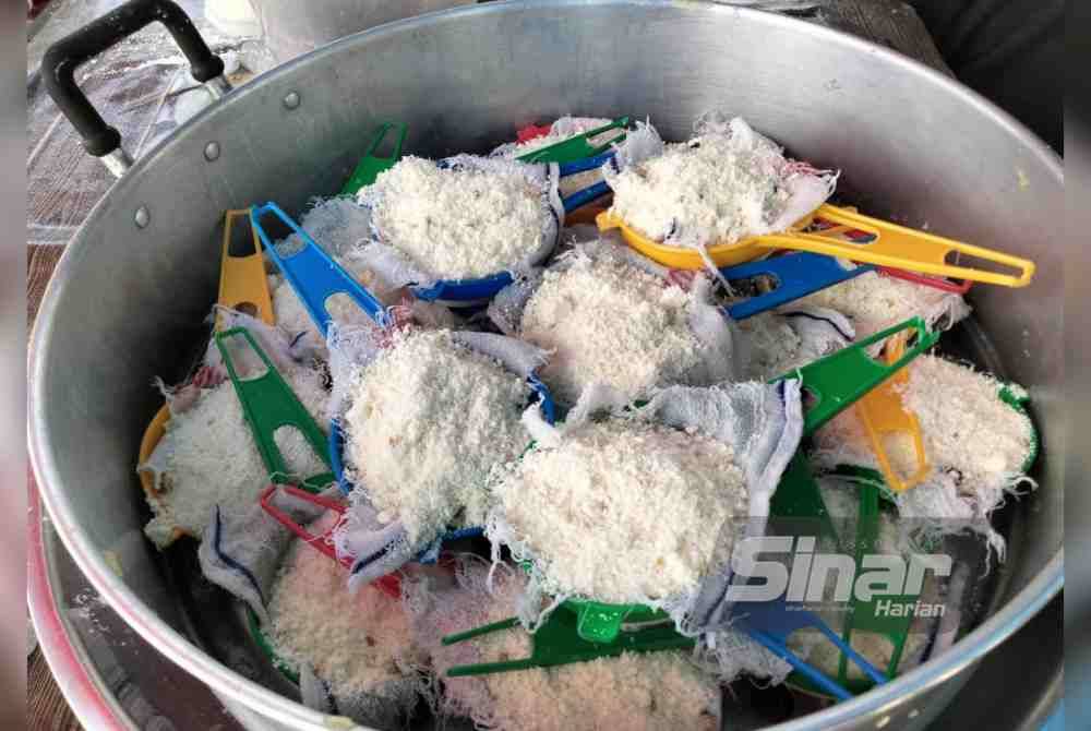 Ubi kayu parut diisi dalam penapis teh sebelum dikukus menjadi kuih putu halba.