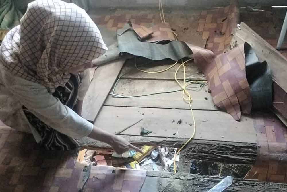 Nur Adira menunjukkan keadaan lantai rumah mereka yang sudah reput.