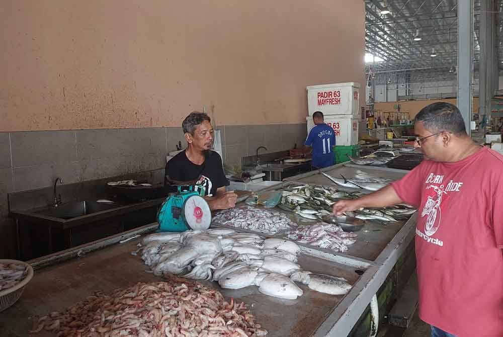 Pelanggan meninjau harga ikan dan makanan laut di Pasar Payang, Kuala Terengganu.