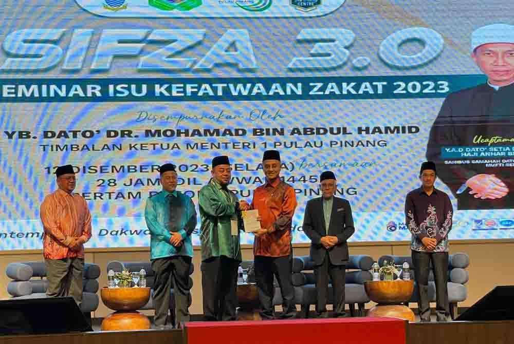 Amran (tiga dari kiri) menyerahkan Buku Isu Zakat Kontemporari di sebuah hotel di Bertam ketika merasmikan Seminar Isu Kefatwaan Zakat 2023 (SIFZA 3.0) dan meluncurkan Buku Isu Zakat Kontemporari.