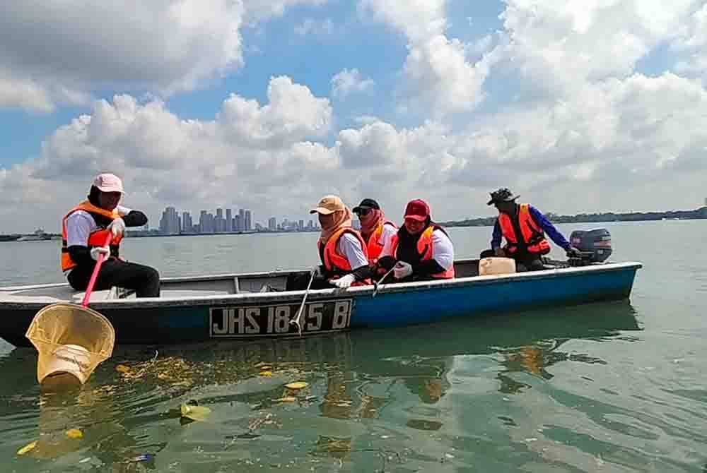 Sukarelawan mengutip sampah di kawasan perairan dekat Kampung Sungai Melayu, Iskandar Puteri.