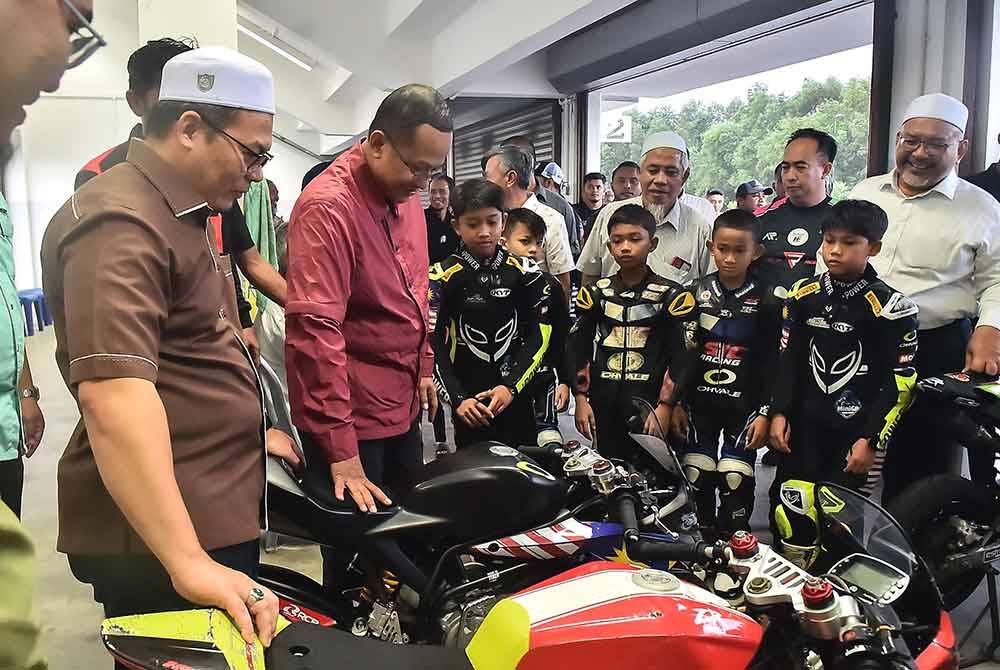 Ahmad Samsuri (dua dari kiri) bersama Hishamuddin (kiri) dan Wan Sukairi (kanan) melihat motosikal yang digunakan pelumba-pelumba cilik Terengganu.