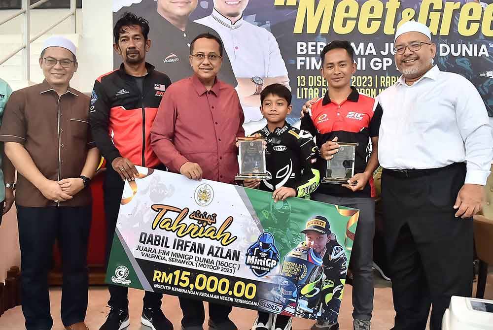 Ahmad Samsuri (tiga dari kiri) menyerahkan insentif kepada Qabil Irfansempena program Exclusive Meet And Greet With World Champions FIM Mini GP 2023 di Litar Permotoran Gong Badak, di Kuala Nerus.