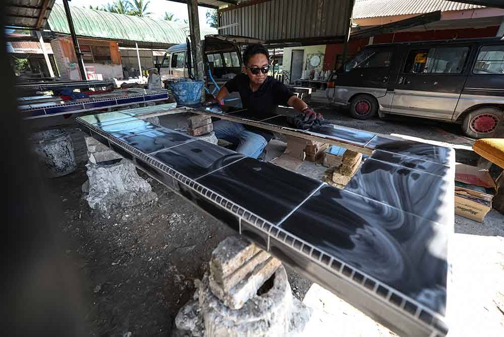 Amir melakukan proses mengilap kepok kubur sewaktu kerja-kerja pembuatan batu nisan. - Foto Bernama