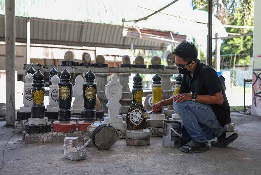 Amir mengecat batu nisan dengan cat pengilat. - Foto Bernama