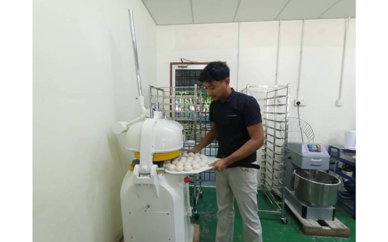 Muhamad Syirazi menunjukkan mesin menguli doh untuk membuat roti burger.