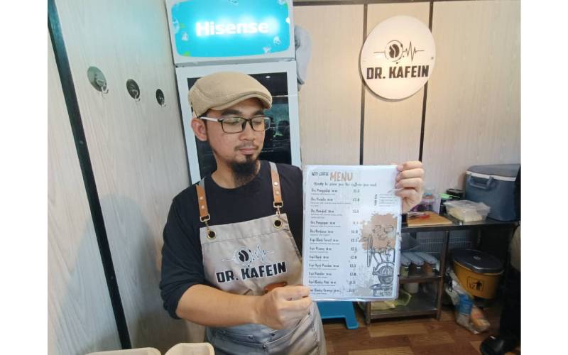 Muhammad Asyraf menunjukkan aneka menu kopi Dr. Kafein yang dijual kepada pelanggan.