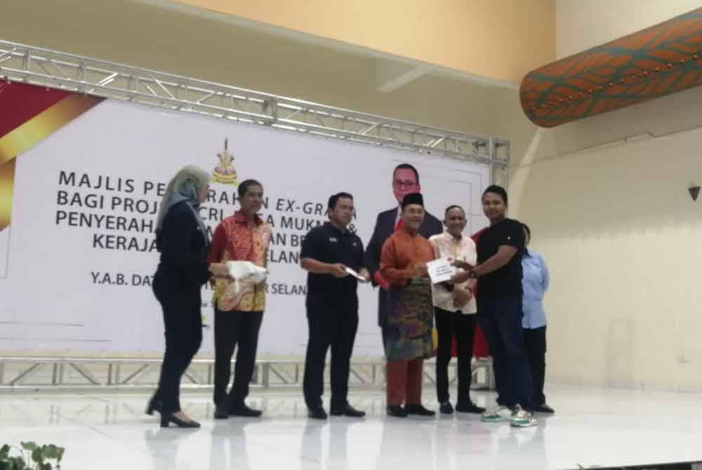 Borhan (empat dari kiri) menyampaikan ex-gratia kepada salah seorang penduduk Desa Mukmin yang terlibat dengan jajaran ECRL.