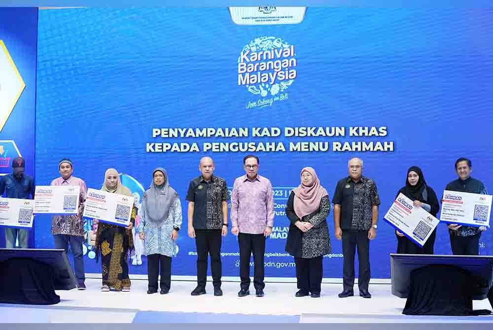 Anwar (tengah) bersama Armizan (lima dari kiri) dan Timbalan KPDN, Fuziah Salleh (empat dari kanan) bergambar bersama pengusaha Menu Rahmah selepas menyampaikan Kad Diskaun Khas pada majlis perasmian Karnival Barangan Malaysia (KBM) 2023 diadakan pada Khamis.