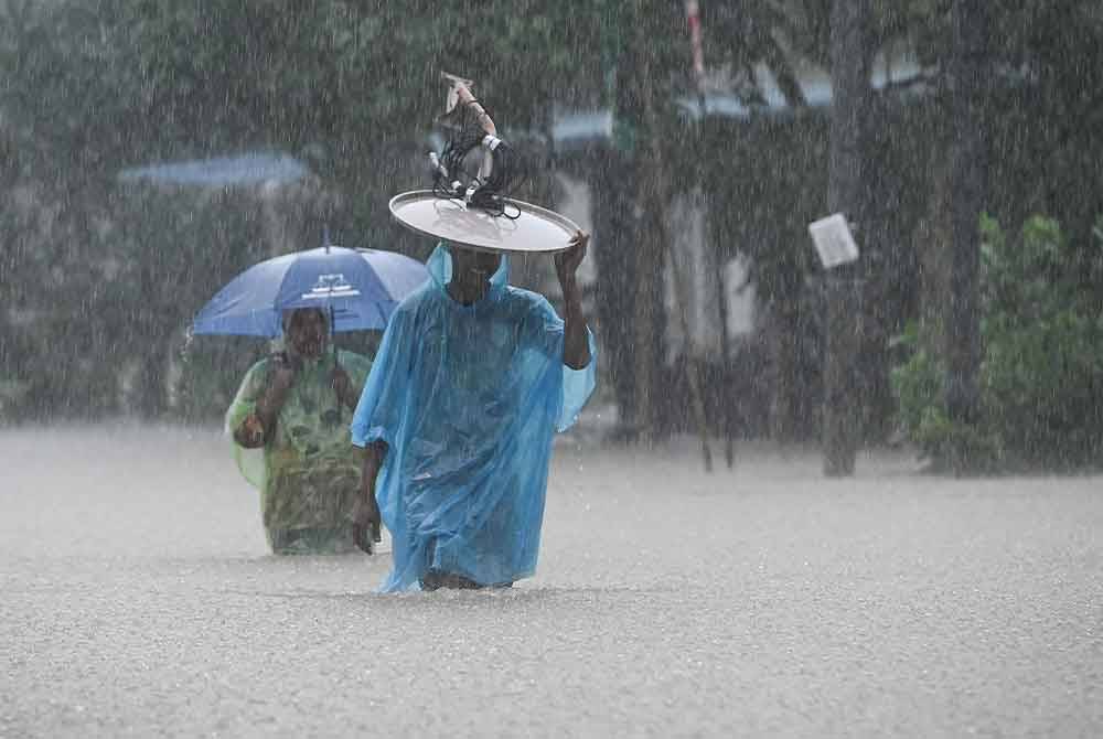 Penduduk meredah banjir dengan membawa barangan keperluan untuk ke Pusat Pemindahan Sementara (PPS) selepas kawasan berkenaan dinaiki air ketika tinjauan di Kampung Menerong hari ini.