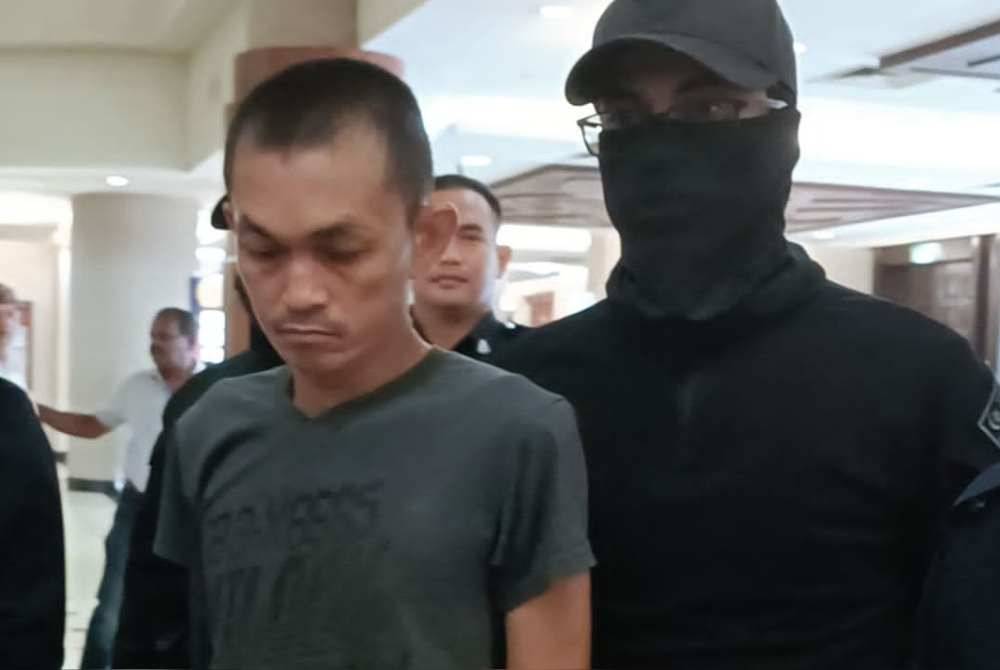 Afendi (kiri) yang memakai baju T berwarna hitam dibawa ke Mahkamah Majistret Kuala Lumpur pada Jumaat, atas dua pertuduhan membunuh ibu bapanya di Kampung Sungai Penchala, Sabtu lalu.