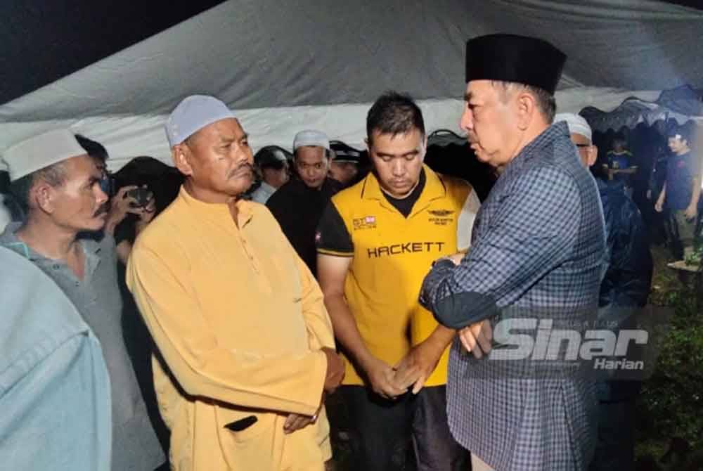 Muhamad Zaki menenangkan suami Nor Faizah (dua dari kanan) selepas pengebumian di Tanah Perkuburan Islam Kampung Pintu Gerbang.