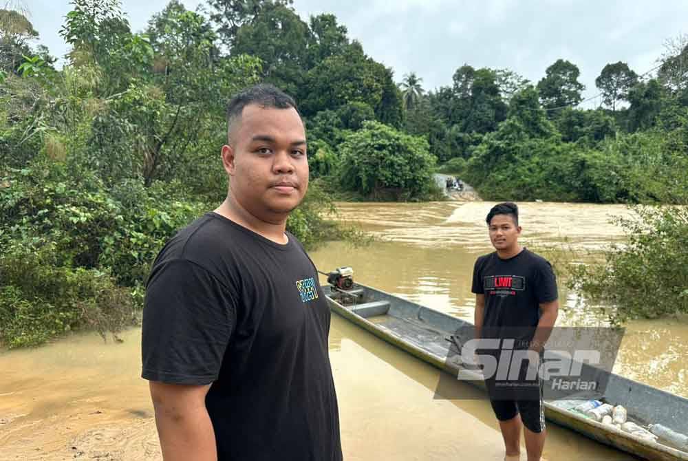 Ahmad Hidayat (kiri) melihat jambatan yang tenggelam di tengah-tengah sungai.