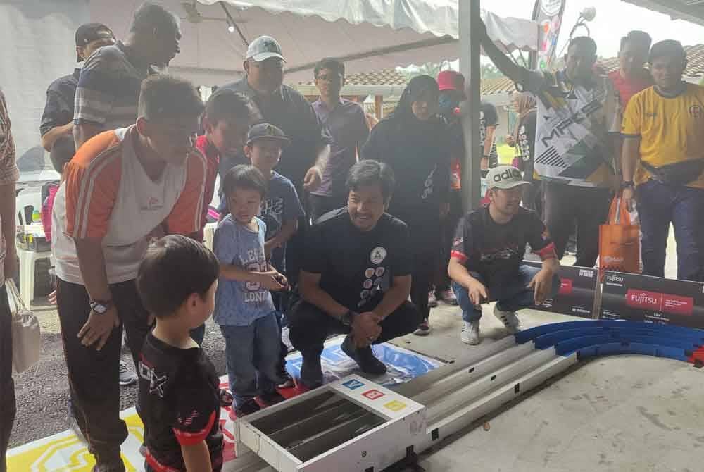 Mohd Najwan (duduk dua dari kanan) menyaksikan trak litar kereta lumba mainan pada program berkenaan.