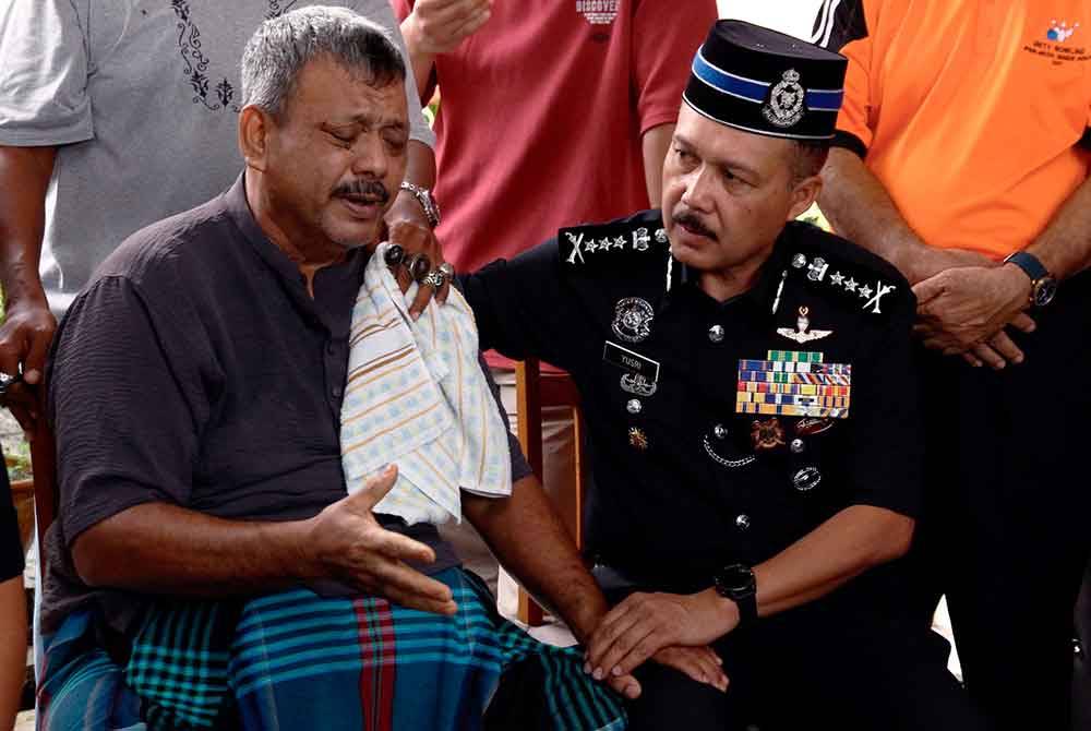 Mohd Yusri (kanan) menenangkan Muhd Zamrie Zainal Abidin, 55, (kiri) bapa kepada pelajar yang maut akibat dilanggar sebuah kereta berhampiran SMK Jati di kediaman keluarganya di Taman Chepor Sentosa Chemor pada Sabtu. - Foto Bernama